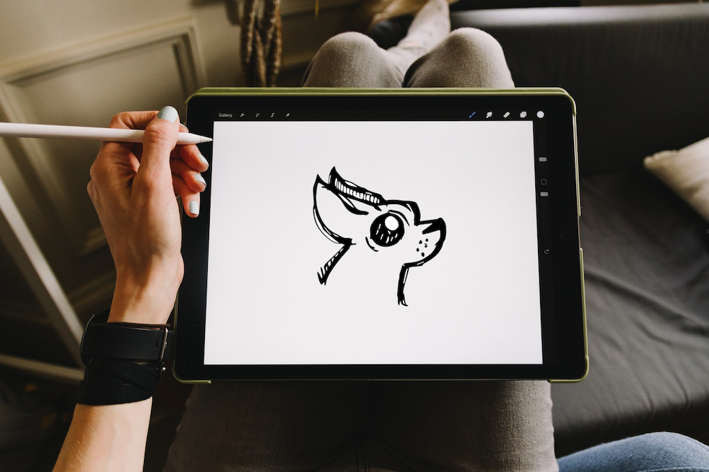 a woman drawing a black chihuahua on an ipad